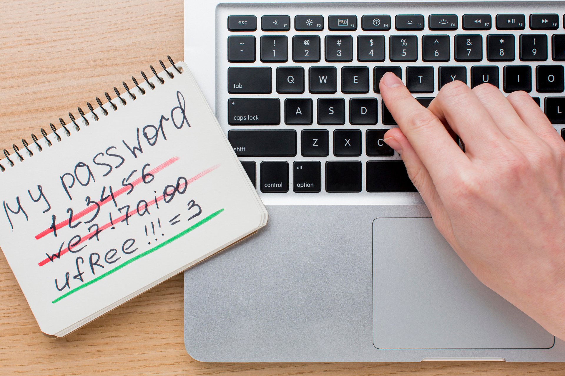 flat-lay-laptop-with-hands-notebook-with-password-information